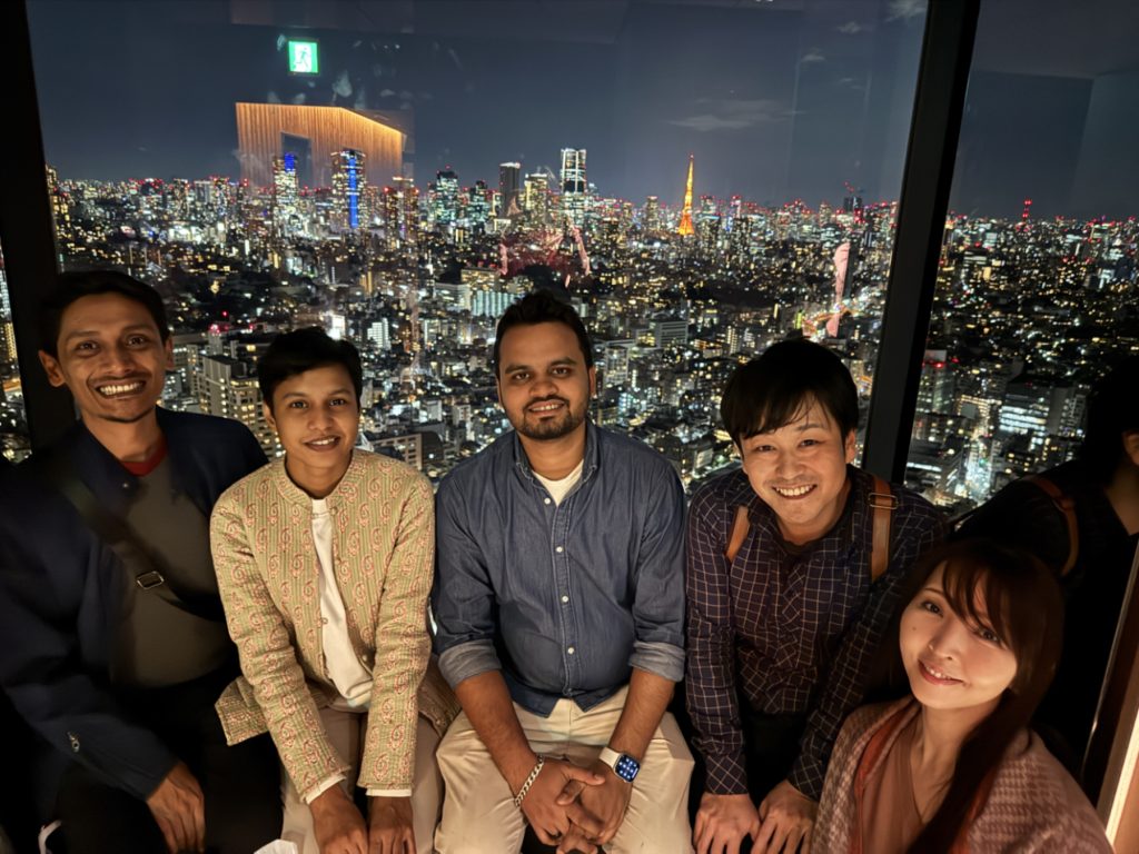 Group photo of the Bangladeshi winning director and Studio PADMA organizer celebrating the DigiCon6 ASIA award, with the illuminated Tokyo Tower in the background.
